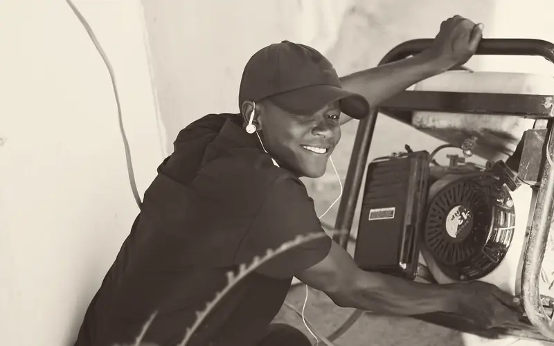 Man checking a portable generator set up outdoors against a wall