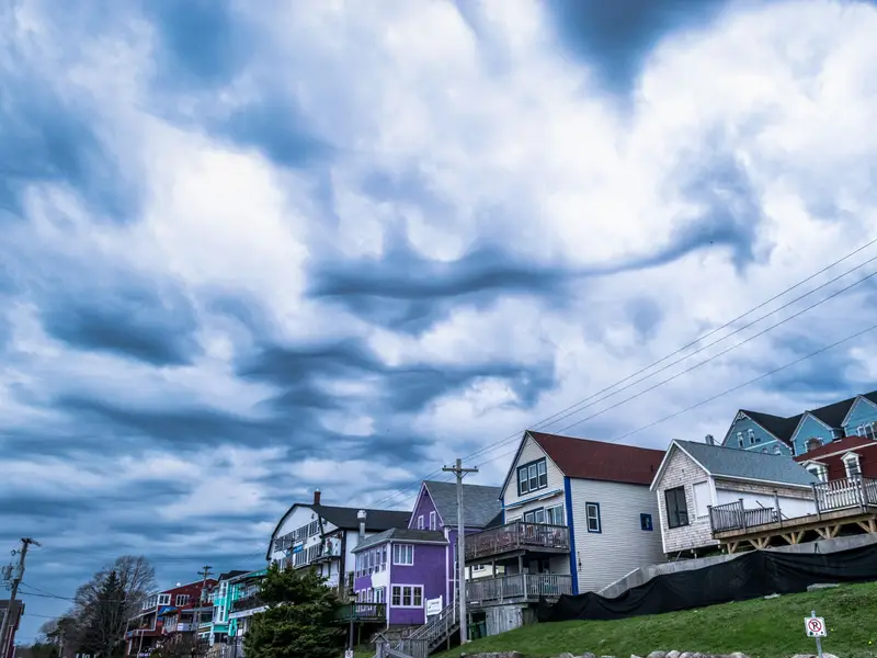 Heavy storm clouds rolling in over a row of wooden houses on a hill